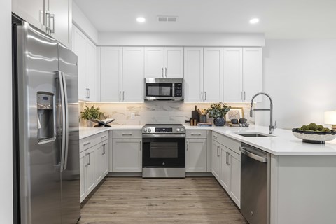 A modern kitchen with a refrigerator on the left and a sink on the right.