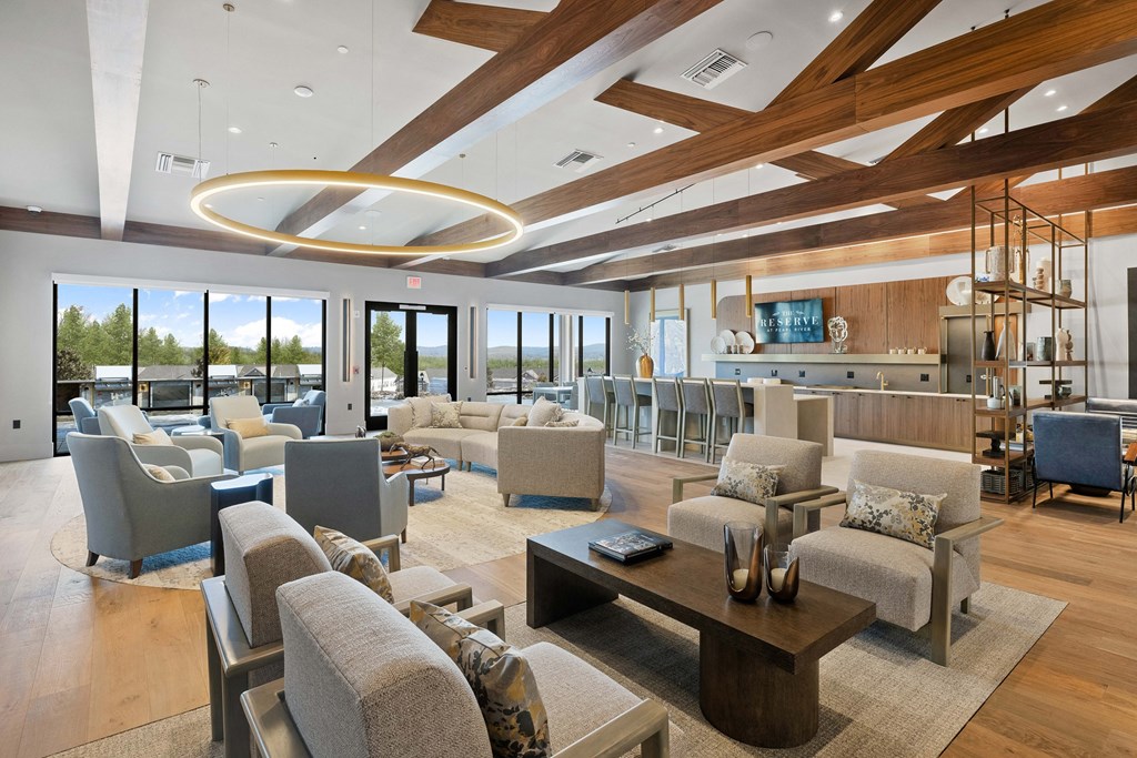 A modern living room with a large circular light fixture and a view of the outdoors through the windows at The Reserve at Pearl River Apartments, Pearl River, NY, 10965