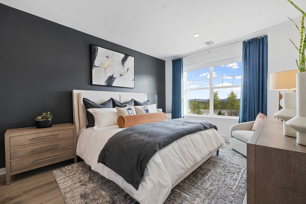 A bedroom with a large bed, a nightstand, and a chair at The Reserve at Pearl River Apartments, Pearl River, 10965