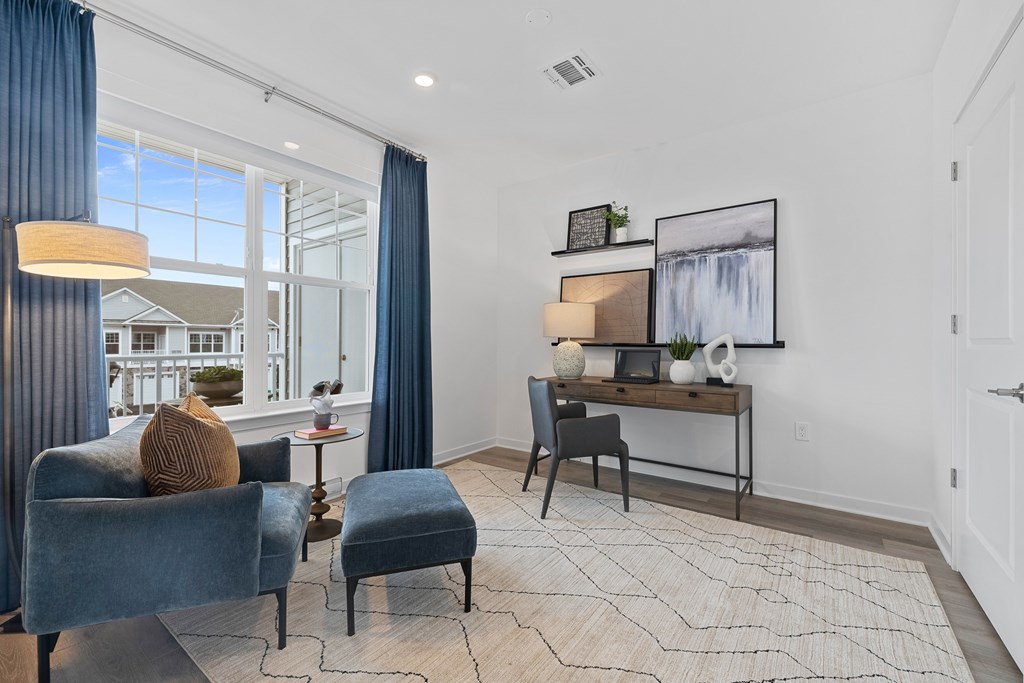 A living room with a blue chair and a small table with a vase on it. at The Reserve at Pearl River Apartments, Pearl River, New York
