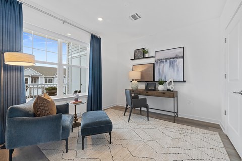 A living room with a blue chair and a small table with a vase on it.