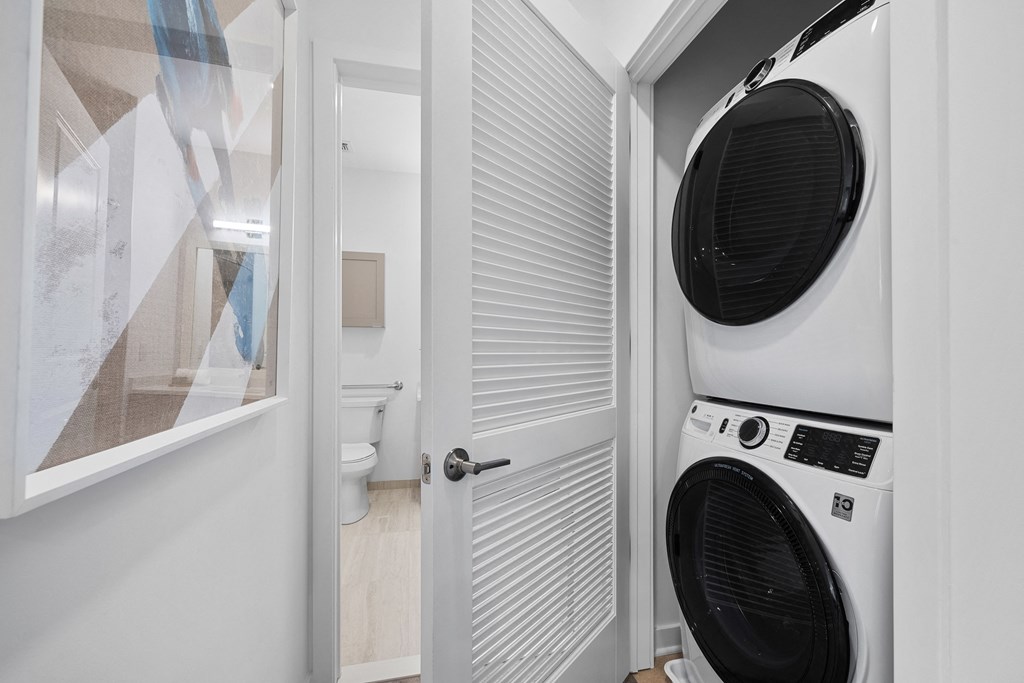 A white washing machine is in a small laundry room at The Reserve at Pearl River Apartments, New York