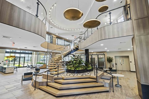 A modern atrium with a staircase and hanging lights.