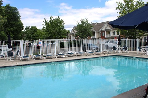 a swimming pool with chairs and umbrellas next to a fence