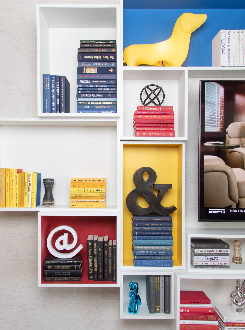 a bookshelf filled with books and a yellow bird on top