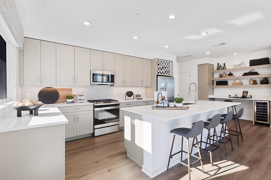 a large white kitchen with a large island and bar stools