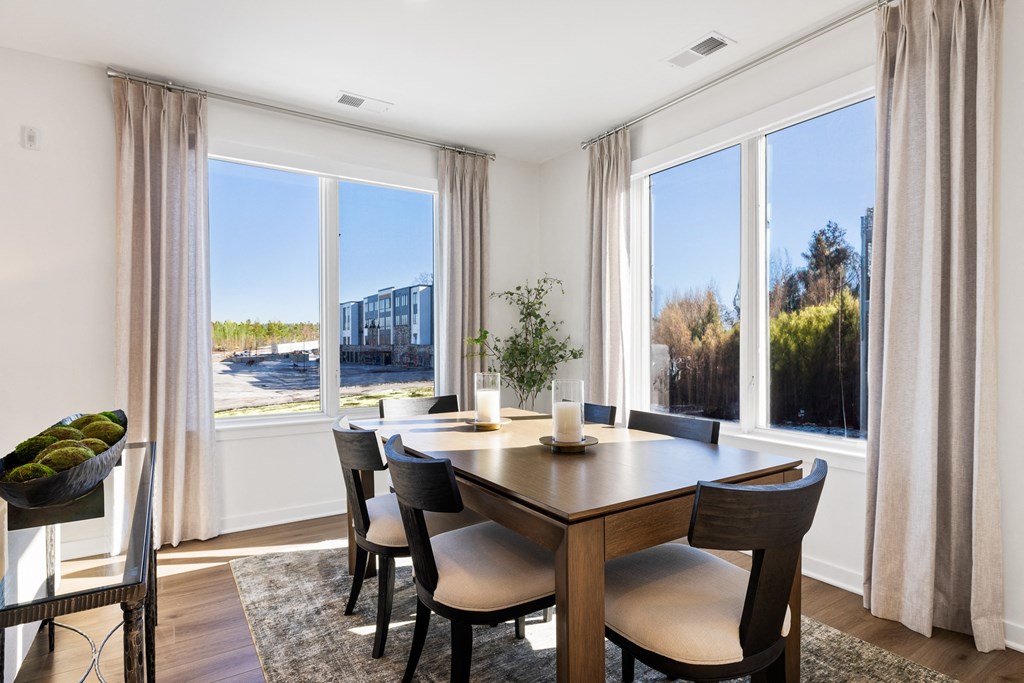 a dining room with large windows and a wooden table and chairs a dining room with large windows and a wooden table and chairs at Stonehill at West Orange, New Jersey, 07052