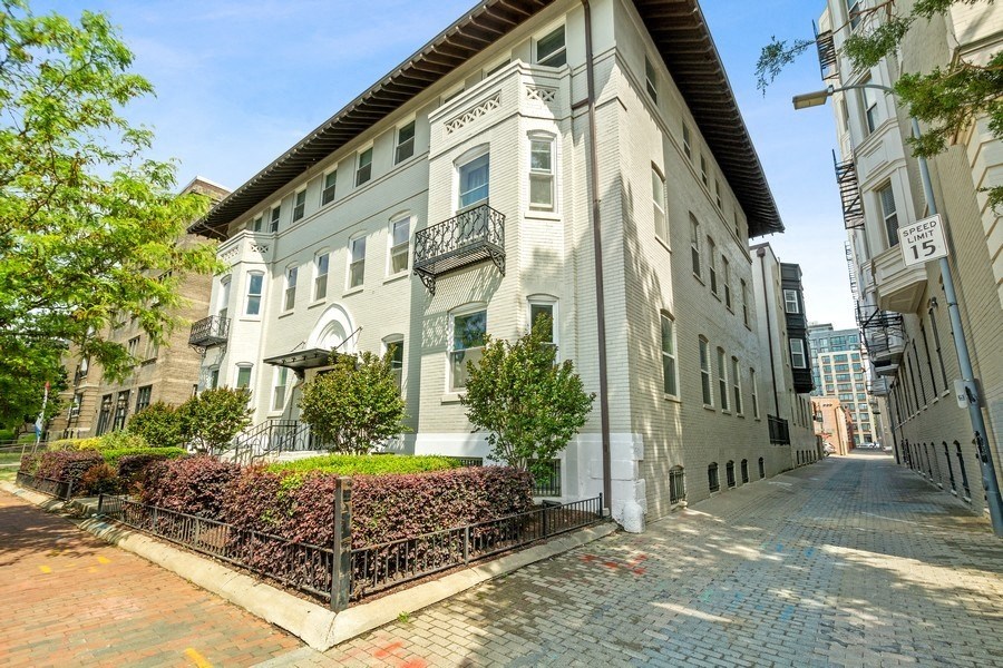 a grey apartment building with a brick sidewalk in front of it