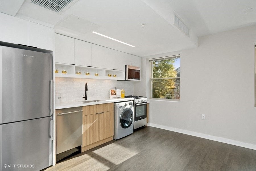 a kitchen with white cabinets and stainless steel appliances at Carver and Slowe Apartments, Washington Washington, DC