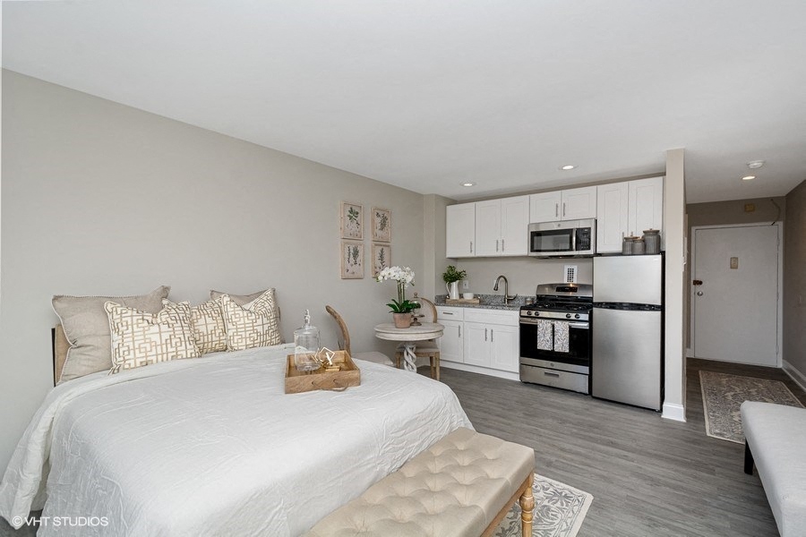 a bedroom with a bed and a kitchen in the background