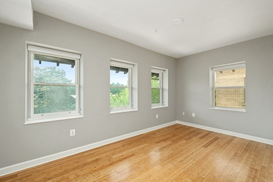 a bedroom with a hardwood floor and four windows