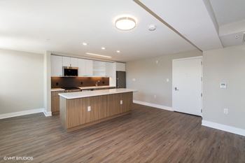 an empty living room with a kitchen in the background at Carver and Slowe Apartments, Washington