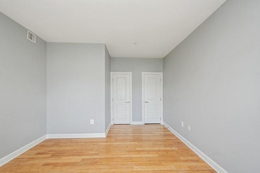 a bedroom with grey walls and a wooden floor