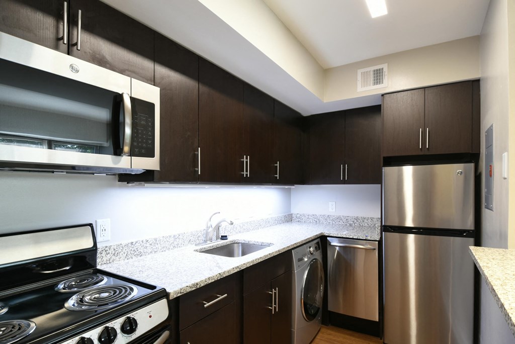 a kitchen with dark cabinets and stainless steel appliances
