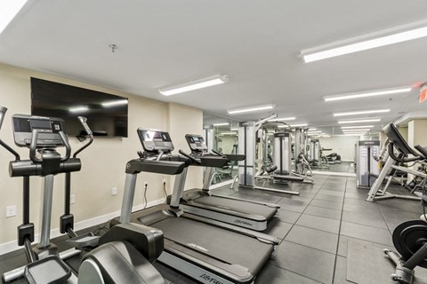 a gym with cardio machines and a flat screen tv at Carver and Slowe Apartments, Washington