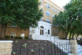 a large brick building with stairs and trees in front of it