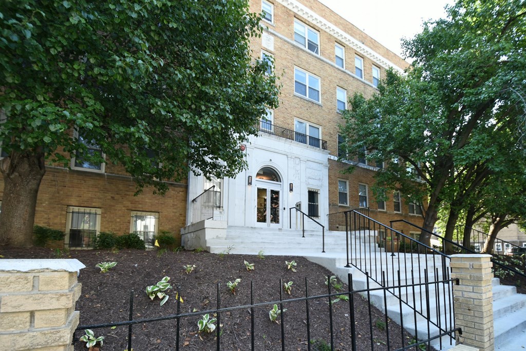 a large brick building with stairs and trees in front of it