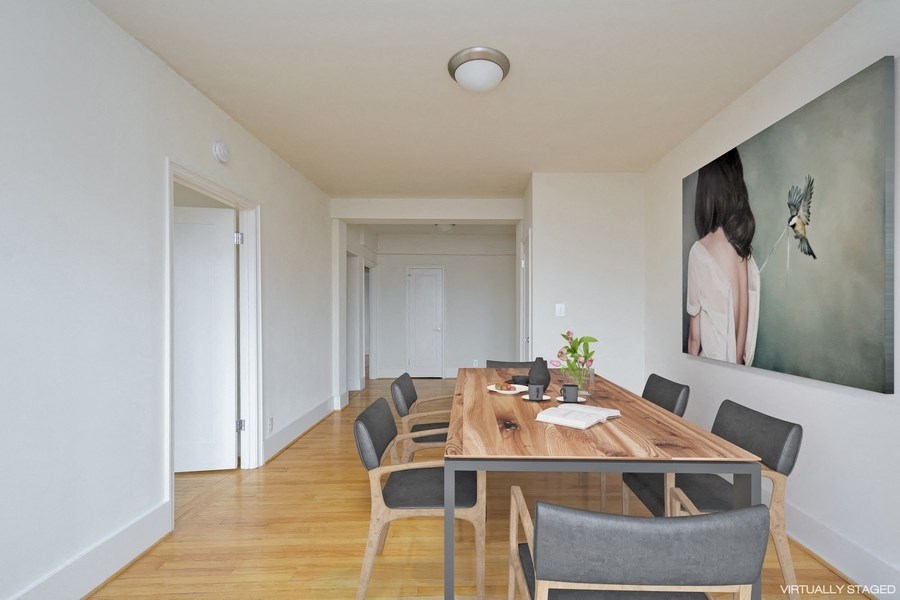 a room with a wooden table and chairs and a large painting on the wall