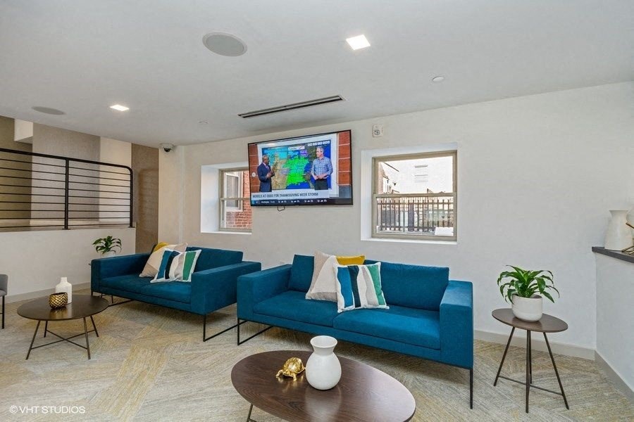 a living room with blue couches and a flat screen tv at Carver and Slowe Apartments, Washington Washington, DC
