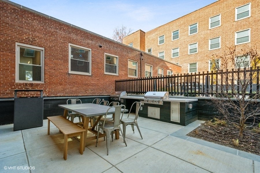 a patio with a table and chairs and a grill in front of a brick building at Carver and Slowe Apartments, Washington, DC