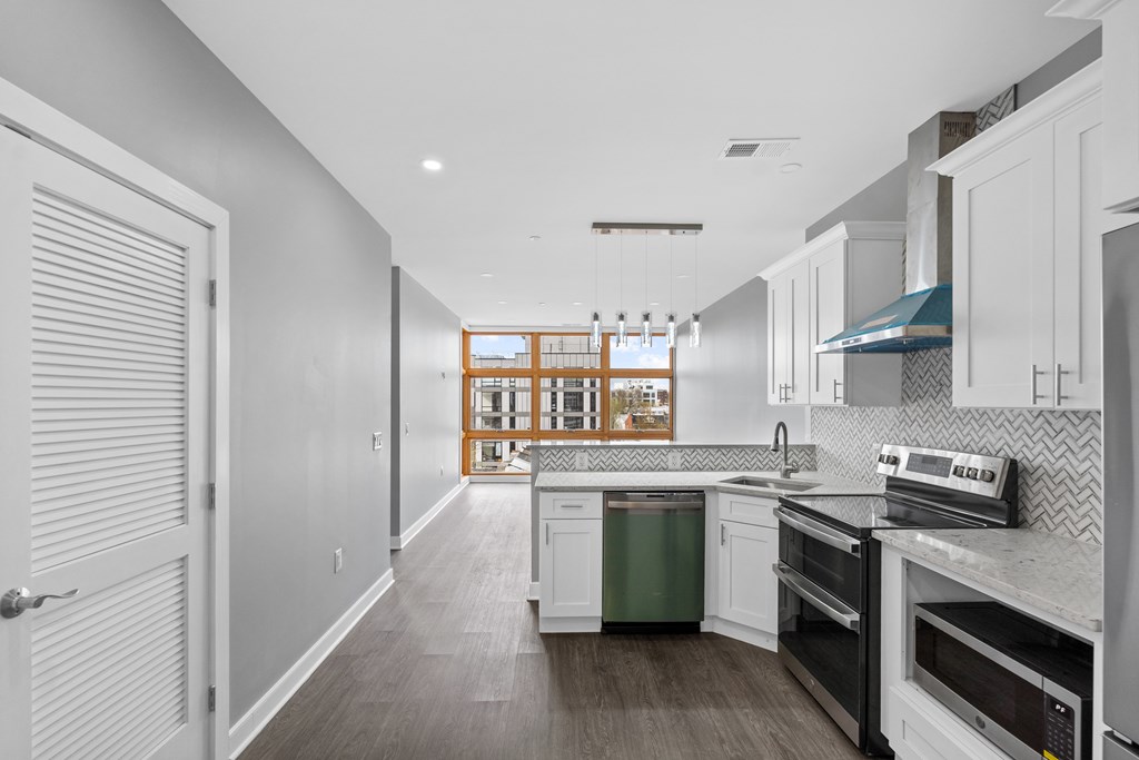 A modern kitchen with white cabinets and a green trash can.