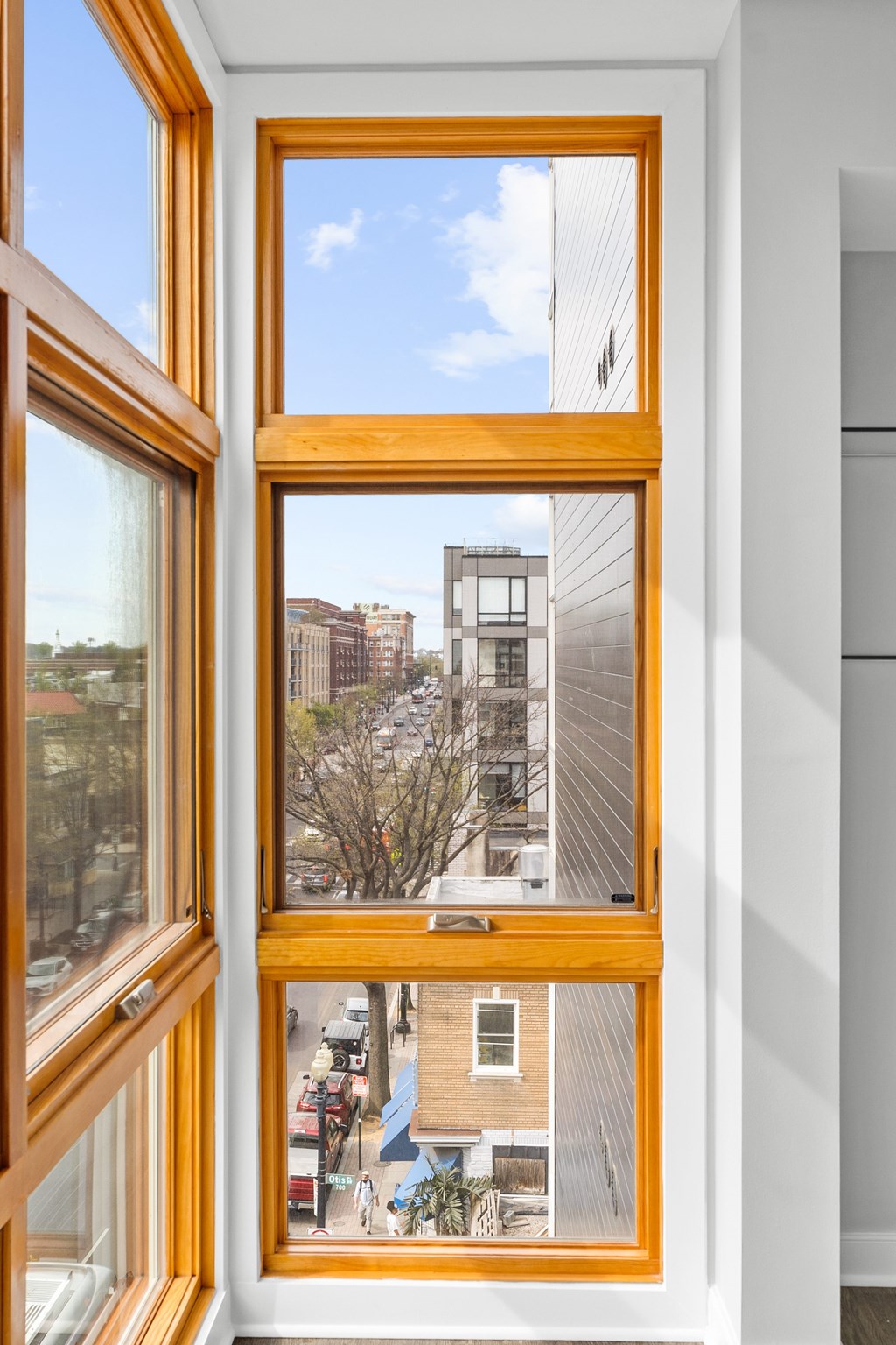 A view of a city from a window with a wooden frame.