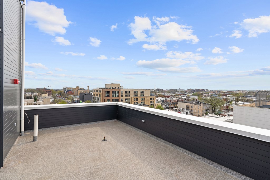 A rooftop patio with a concrete floor and a metal railing.