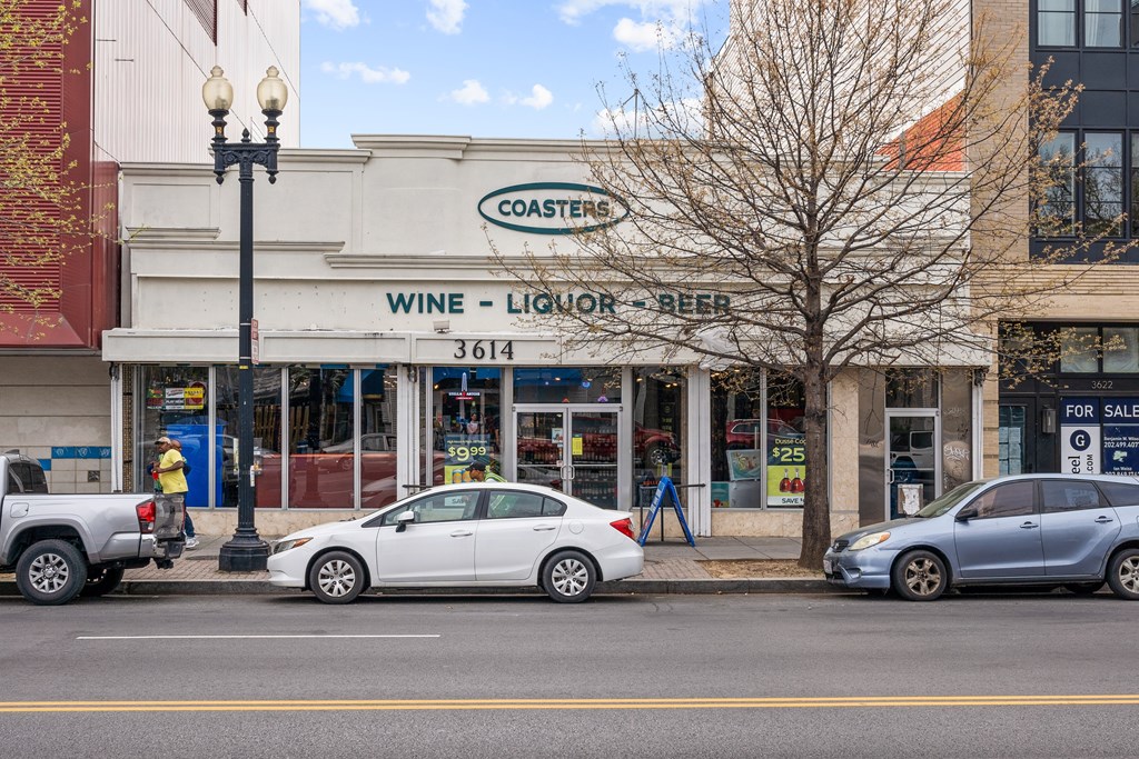 A white car is parked in front of a liquor store.