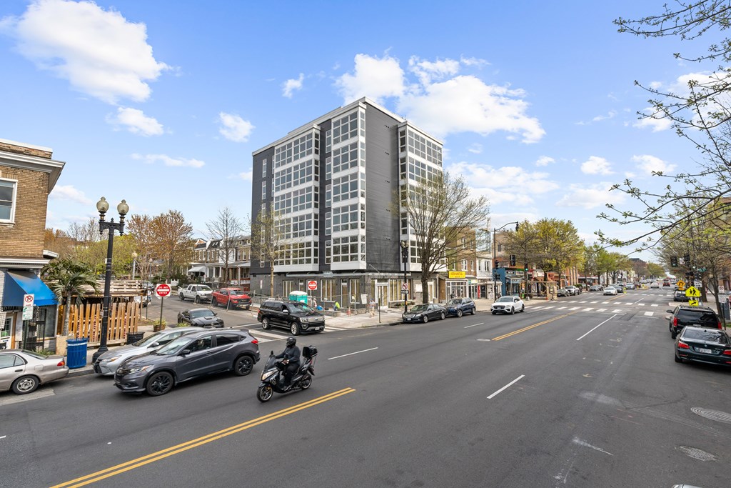 A motorcycle is riding on a street with cars and buildings on both sides.