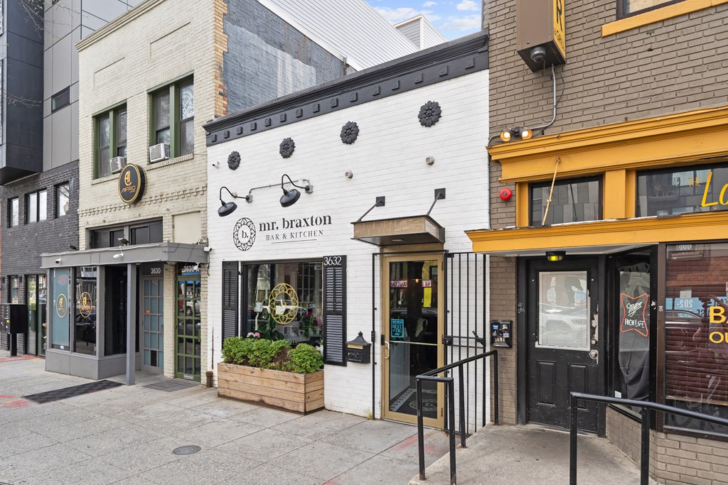 A white building with a black awning and a sign that says Mr. Braxton Bar & Kitchen.