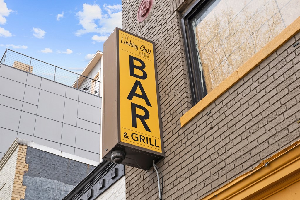 A sign for a bar and grill is hanging from a building.