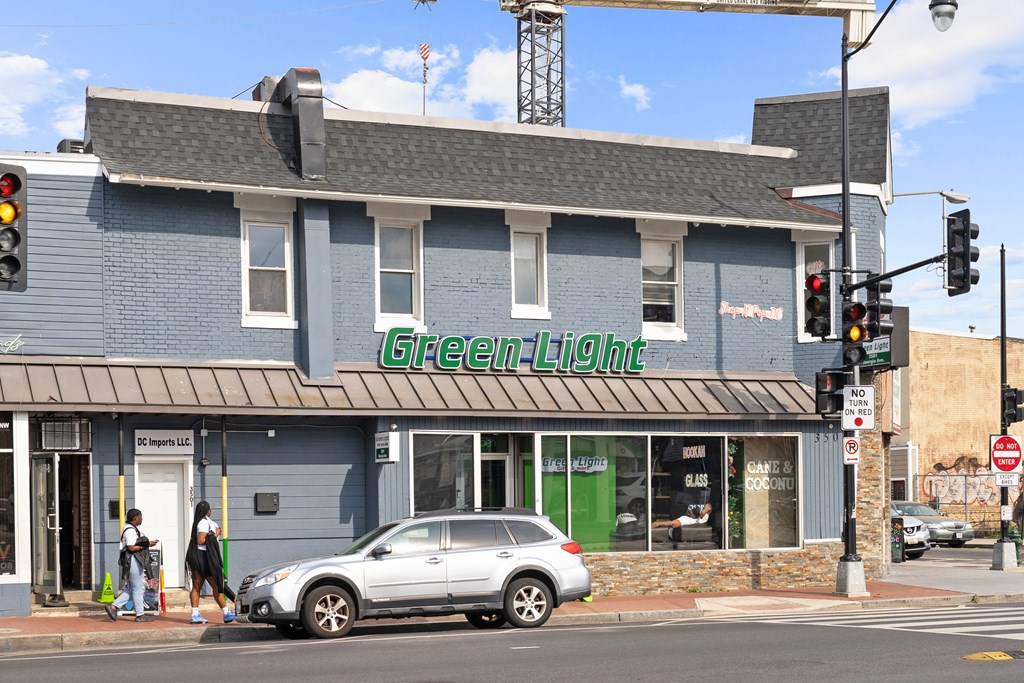 A car is parked in front of a building with a green light on.