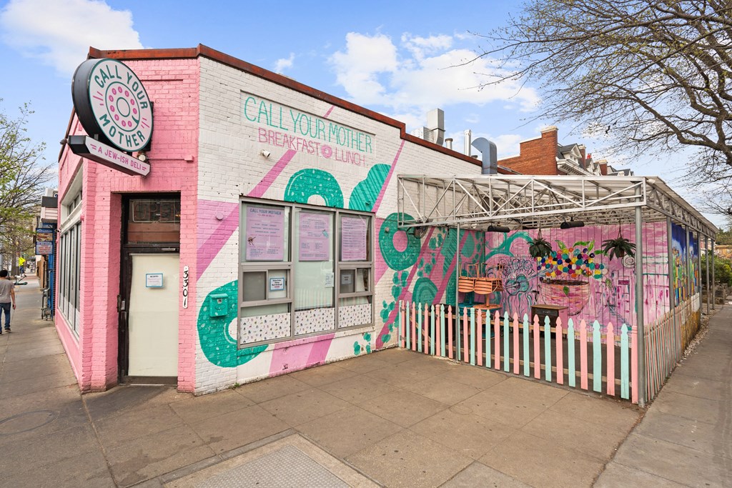 A pink building with graffiti and a sign that says "Call Your Mama".