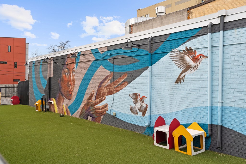 A mural of a woman and a bird is painted on a blue wall.