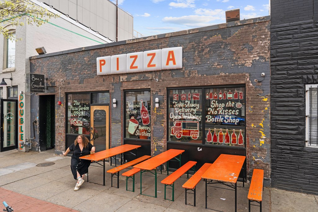 A woman walks past a pizza shop.