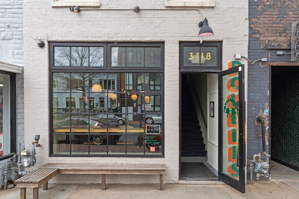 A white building with a black door and a window with a reflection of a car and some lights.