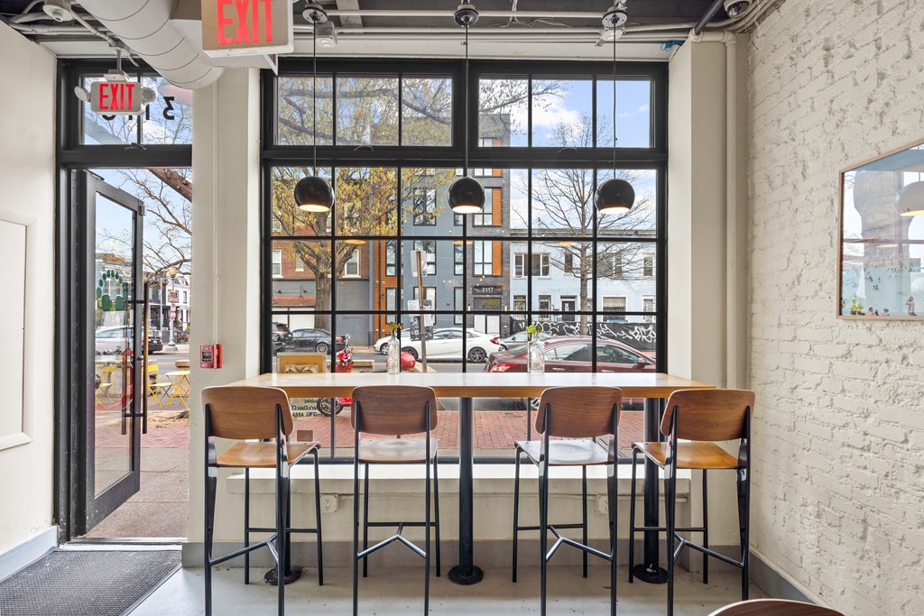 A white brick wall with a table and chairs in front of a window.