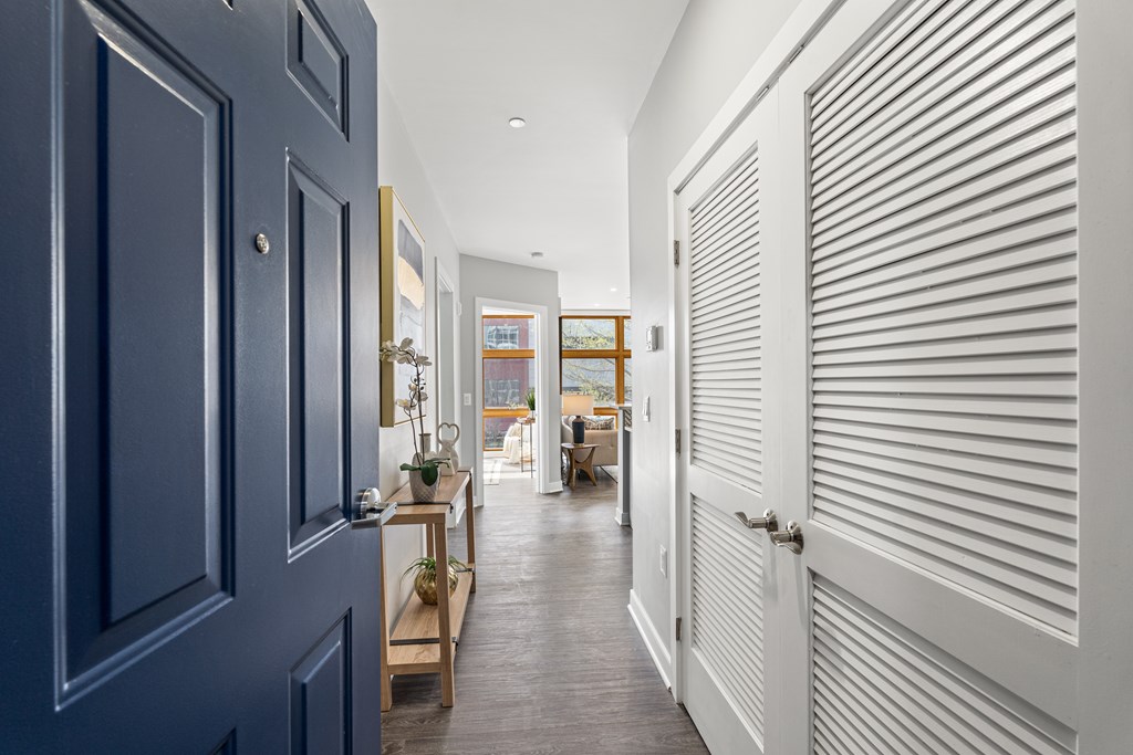 A hallway with a blue door on the left and a white door on the right.