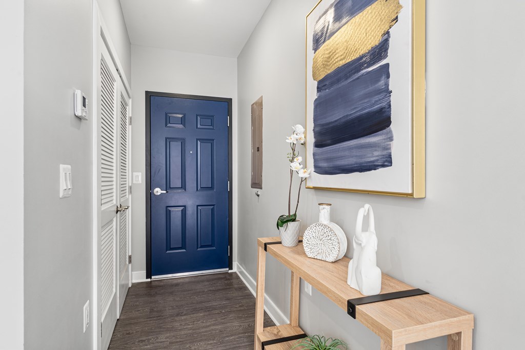 A hallway with a blue door and a painting on the wall.