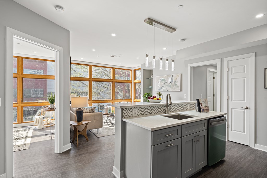 A modern kitchen with a large island and a view of the outdoors through the windows.