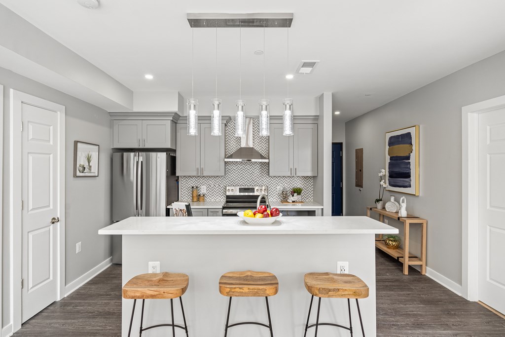 A kitchen with a white island and wooden stools.
