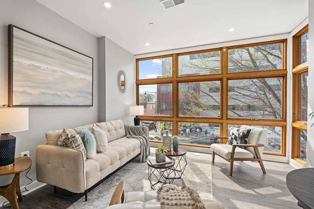 A living room with a large window and a painting on the wall.