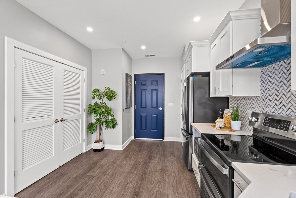 A kitchen with a blue door and white cabinets.