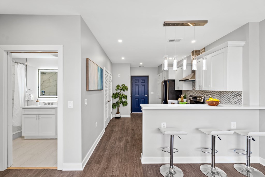 A modern kitchen with white cabinets and a bar area.