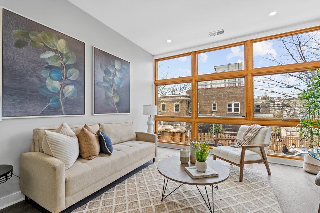 A living room with a couch, a chair, and two paintings on the wall.