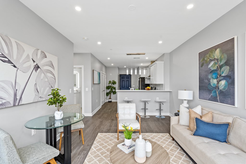A modern living room with a glass table and a grey sofa.
