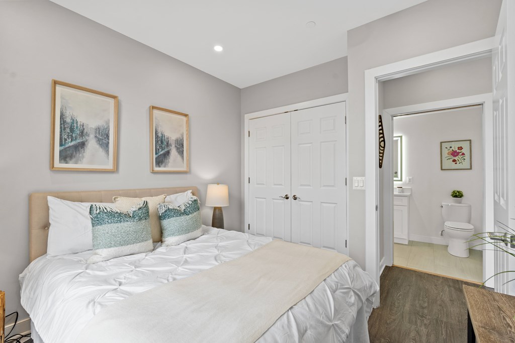 A bedroom with a large bed and two pictures on the wall.