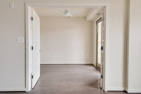 an empty living room with white walls and a ceiling fan