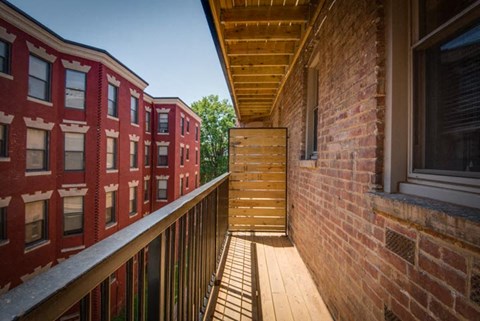 a balcony with a wooden railing and a brick building in the background