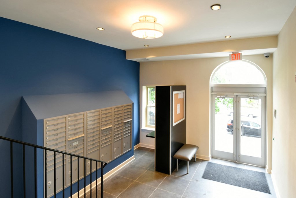 a hallway with blue walls and a staircase with a chair and lockers